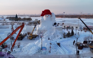 哈尔滨迎来今冬首个大雪人：高约20米，右手托举着一个红色的火炬 ！
