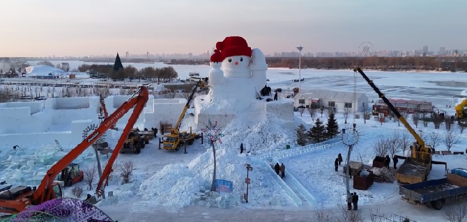 哈尔滨迎来今冬首个大雪人：高约20米，右手托举着一个红色的火炬 ！-第1张图片